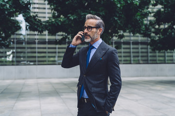 Handsome mature businessman calling by smartphone at street