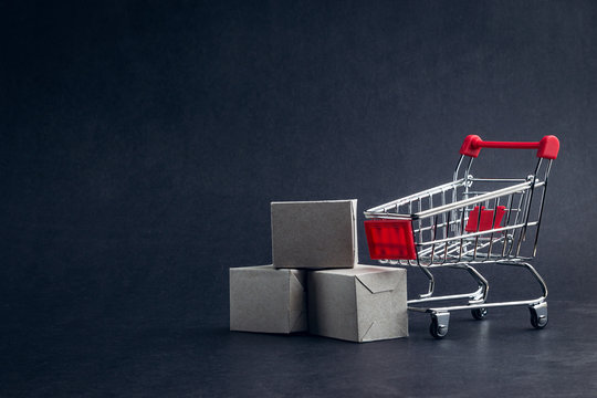 Shopping cart and box on dark background, business, shopping concept. Selective focus