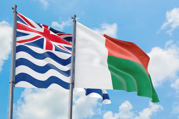 Madagascar and British Indian Ocean Territory flags waving in the wind against white cloudy blue sky together. Diplomacy concept, international relations.