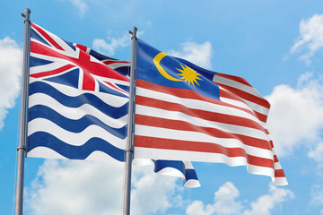 Malaysia and British Indian Ocean Territory flags waving in the wind against white cloudy blue sky together. Diplomacy concept, international relations.