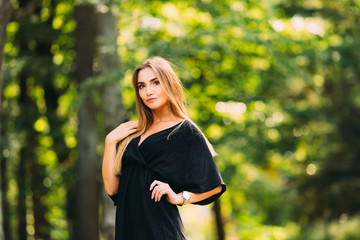 A young woman in a black dress holds her hand at her waist in th