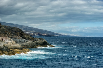 East coast of Tenerife. Rocky coastline and azure sea. Waves constantly hitting the rocky shore.