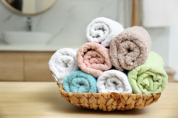 Fototapeta na wymiar Rolled fresh towels on wooden table in bathroom, closeup