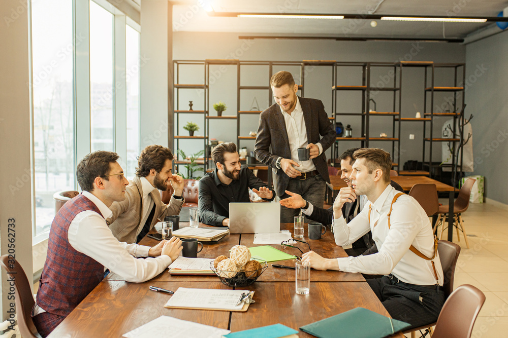 Wall mural coworking of young business team gathered in office together, discussing and sharing opinons, wearin