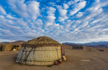 Pamirian yurt in the mountains against the background of a cloudy blue sky