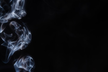 Abstract puffs of smoke on the left side of the frame on a dark background with a place for text, mysticism, fantasy