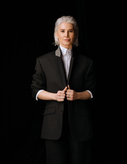 Business senior woman in white shirt and black blazer, on black background