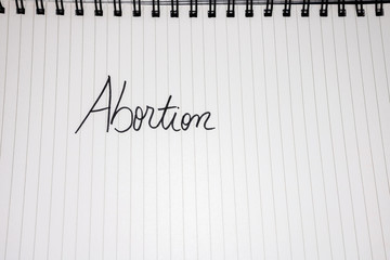 Abortion handwriting  text on paper, on office agenda. Copy space.