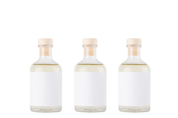 Three glass bottles for cosmetic, perfume, alcohol drink with  white label, cork, yellow liquid isolated on white background, mock up for design.