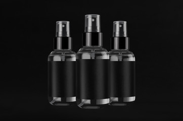 Three exquisite transparent spray dispenser bottles for cosmetics with black label on black background, mock up for branding,  presentation, design.