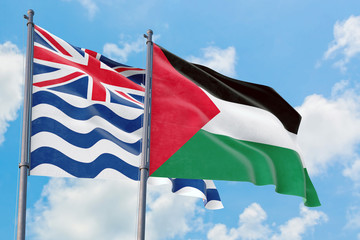 Palestine and British Indian Ocean Territory flags waving in the wind against white cloudy blue sky together. Diplomacy concept, international relations.