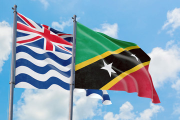 Saint Kitts And Nevis and British Indian Ocean Territory flags waving in the wind against white cloudy blue sky together. Diplomacy concept, international relations.