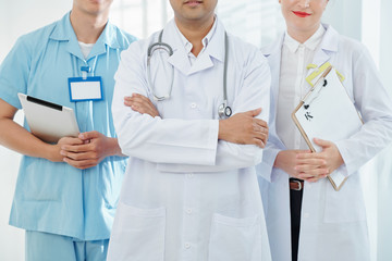 Cropped image of confident general practitioner and his coworkers with digital tablet and prescription documents