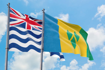 Saint Vincent And The Grenadines and British Indian Ocean Territory flags waving in the wind against white cloudy blue sky together. Diplomacy concept, international relations.