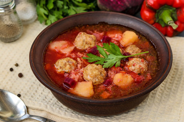 Soup with meatballs and vegetables in a dark bowl