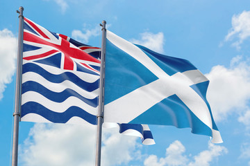 Scotland and British Indian Ocean Territory flags waving in the wind against white cloudy blue sky together. Diplomacy concept, international relations.