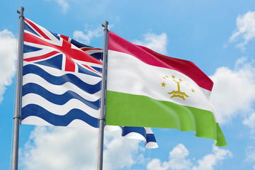 Tajikistan and British Indian Ocean Territory flags waving in the wind against white cloudy blue sky together. Diplomacy concept, international relations.