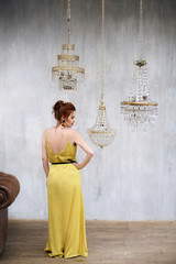 Girl with red head in Art Deco style dressed in yellow dress with red lipstick is standing next to...