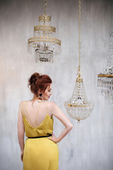 Girl with red head in Art Deco style dressed in yellow dress with red lipstick is standing and...