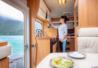 Woman cooking in camper, motorhome interior