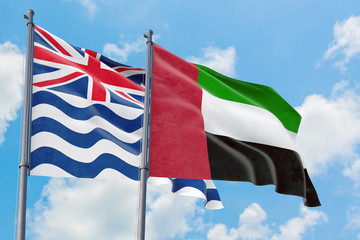 United Arab Emirates and British Indian Ocean Territory flags waving in the wind against white cloudy blue sky together. Diplomacy concept, international relations.