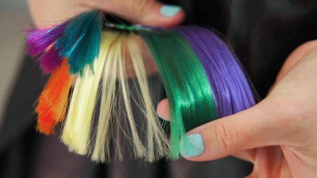 The client of hair salon chooses the color of hair dyeing on catalog. Close up.