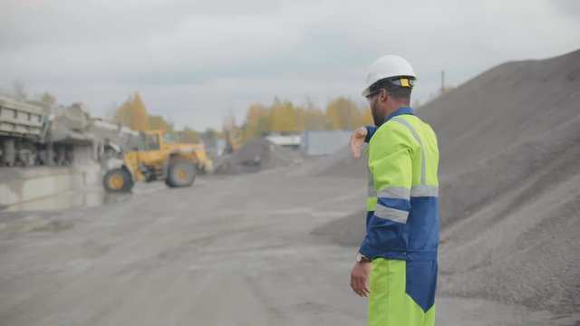 Worker of gravel manufacturing supervising broken stone upload for railroad transportation