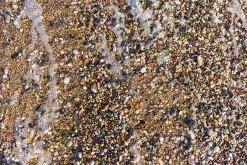 Closeup top view flatlay photography of sandy seashore with splashing sea waves. Abstract natural organic photo background.