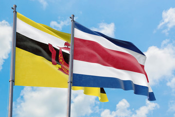 Costa Rica and Brunei flags waving in the wind against white cloudy blue sky together. Diplomacy concept, international relations.