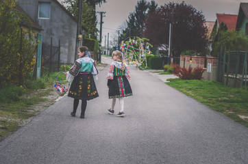 children in traditional folk costumes complimenting on Easter with colorful spring decoration with...