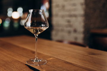 a glass of white wine on a wooden table in a restaurant with panoramic Windows