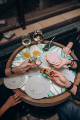 young people are sitting in a cafe eating sandwiches and drinking wine