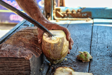 Green fresh coconut peeling and shelling with heavy chop knife for juice.the man using heavy knife to chop green fresh coconut from the tree.coconut cutting weapon
