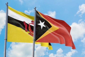 East Timor and Brunei flags waving in the wind against white cloudy blue sky together. Diplomacy concept, international relations.