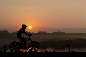 Fototapeta premium Silhouettes Man and bicycle on mountain in the sunlight