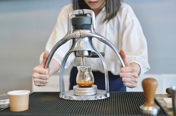 Barista making espresso shot by classic espresso machine