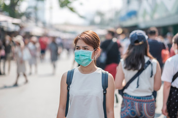 young Asian woman wearing protection mask against Novel coronavirus (2019-nCoV) or Wuhan coronavirus at Chatuchak Weekend Market, landmark and popular for tourists attractions in Bangkok, Thailand