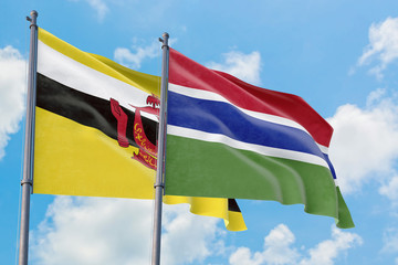 Gambia and Brunei flags waving in the wind against white cloudy blue sky together. Diplomacy concept, international relations.