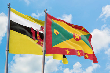 Grenada and Brunei flags waving in the wind against white cloudy blue sky together. Diplomacy concept, international relations.