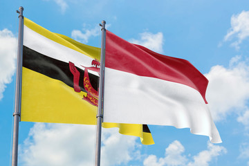 Indonesia and Brunei flags waving in the wind against white cloudy blue sky together. Diplomacy concept, international relations.