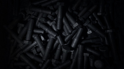 metal bolts scattered on the surface, black color, blurred background