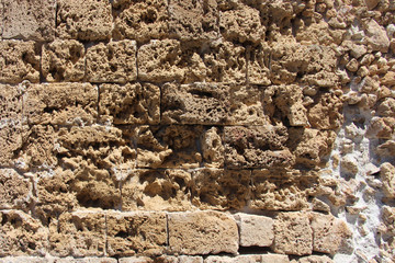 background of a solid stone wall made of cement, limestone, stove, clay and light rectangular bricks with an uneven surface of brown with orange