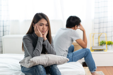 Lover couple relationship problems. Sad young wife sitting on the bed back to back from husband after argument.