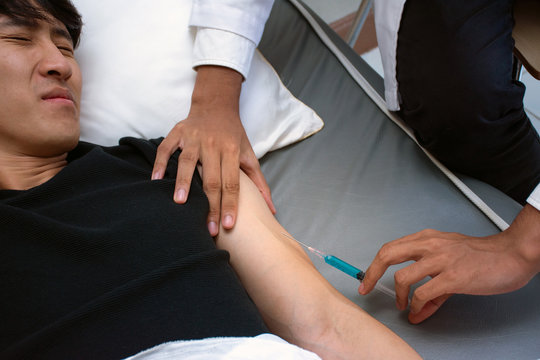 Cropped image of Doctor with Asian patient getting ready for arm injection syringe shot at a hospital