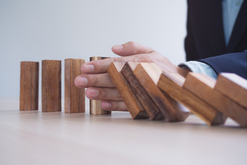 Protection finance from domino effect concept. Hands stop domino effect before destroy stack of money.