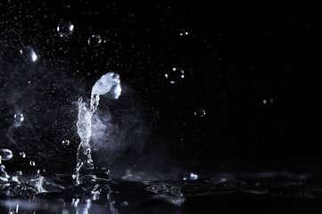Boiling water splash with steam on black background closeup