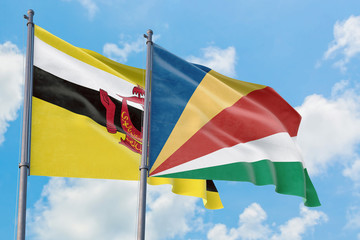 Seychelles and Brunei flags waving in the wind against white cloudy blue sky together. Diplomacy concept, international relations.