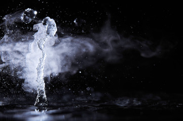Boiling water splash with steam on black background closeup