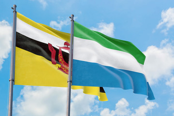 Sierra Leone and Brunei flags waving in the wind against white cloudy blue sky together. Diplomacy concept, international relations.