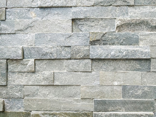 Modern stone rock tile bricks for wall in light grey color with surface left uneven on purpose for decorative effect, made of natural material